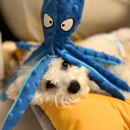 Blue plush octopus toy on a white dog with a yellow blanket