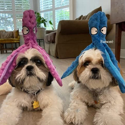 Two small dogs wearing octopus-shaped hats indoors.